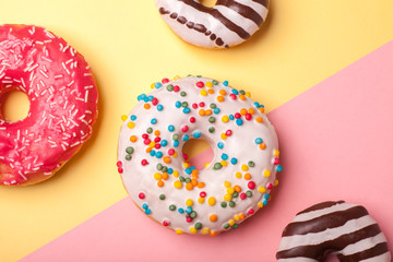 four different glazed donuts on pink-yellow background