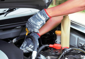 Man checking oil in his car using dipstick