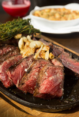 A selection of grilledT Bone steak pieces roasted garlic and rosemary, off the bone on a metal plate