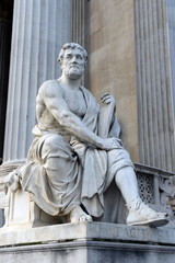 A statue of the Roman historian Tacitus against the building of the Austrian Parliament.