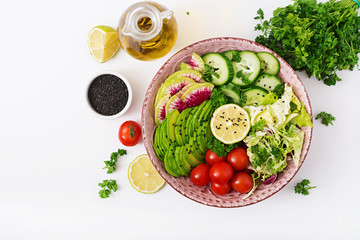 Diet menu. Healthy lifestyle. Vegan salad of fresh vegetables - tomatoes, cucumber, watermelon radish and avocado on bowl. Flat lay. Top view