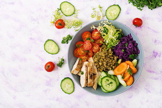 Healthy salad with chicken, tomatoes,  cucumber, lettuce, carrot, celery, red cabbage and  mung bean on  light background. Proper nutrition. Dietary menu. Flat lay. Top view