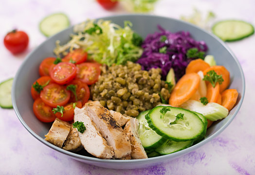 Healthy salad with chicken, tomatoes,  cucumber, lettuce, carrot, celery, red cabbage and  mung bean on light  background. Proper nutrition. Dietary menu.