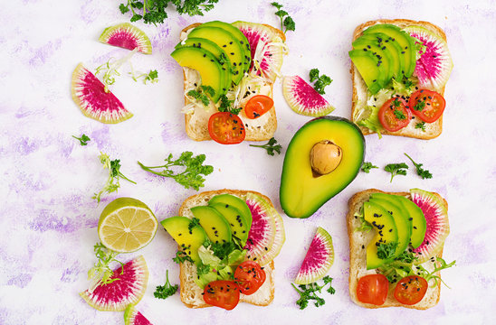 Vegan sandwiches with avocado, watermelon radish and tomatoes on a white background. Flat lay. Top view