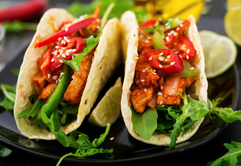 Mexican tacos with chicken fillet in tomato sauce and salsa of paprika and arugula