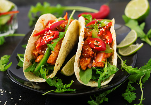 Mexican tacos with chicken fillet in tomato sauce and salsa of paprika and arugula