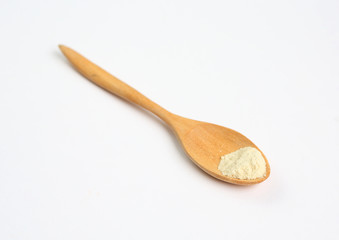 Little powdered milk in wooden spoon over white background