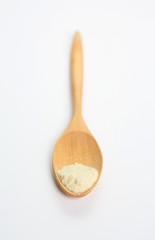 Little powdered milk in wooden spoon over white background