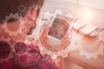 Composite image of man using tablet on wooden table