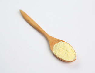 Powdered milk in wooden spoon over white background