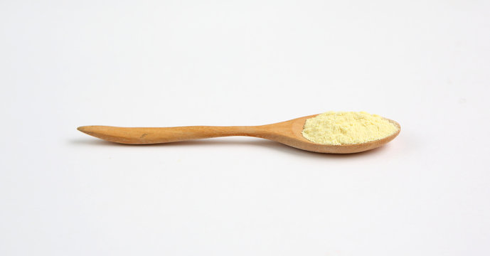 Powdered milk in wooden spoon over white background