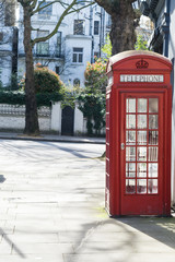 Fototapeta premium London - March 30: Iconic red phone booth in front of white town houses in Kensington on March 30, 2017.