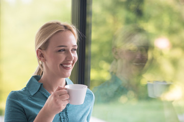 young woman drinking morning coffee by the window