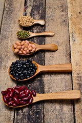 Bean seeds in wooden spoon on vintage style wooden background.