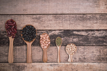 Bean seeds in wooden spoon on vintage style wooden background.