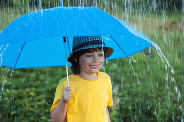 happy boy with umbrella outdoors, child with an umbrella walks in rain