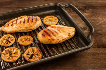 Grilled chicken breasts on the pan, with lemons