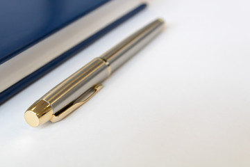 Steel pen and notebook on a white sheet of paper