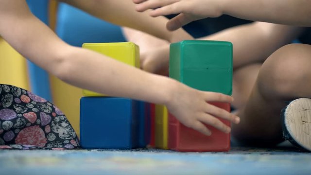 Close-up of child's hands playing with colorful plastic bricks
