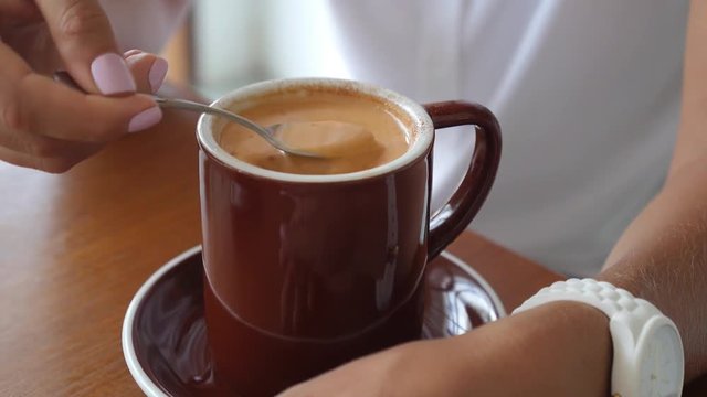 Female Hand Stirring Cup of Hot Chai Latte in Cafe