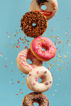 Various decorated doughnuts in motion falling on blue background.