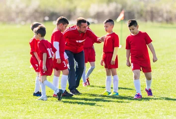 Foto op Plexiglas Kids soccer football - children players with coach at match on soccer field © Dusan Kostic
