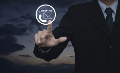 Businessman pressing telephone and mail icon button over sunset sky, Contact us concept