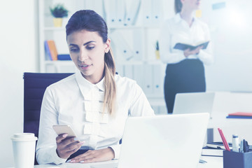 Fototapeta premium Serious woman looking at phone in office