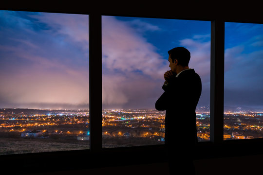 The Man Stand Near The Panoramic Window. Evening Night Time