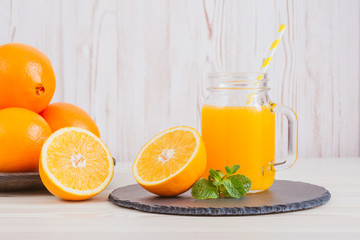 Fresh orange juice in a mason jar and orange sliced ripe on wooden table. Healthy eating concept.