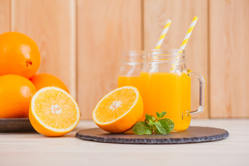 Fresh orange juice in a mason jar and orange sliced ripe on wooden table. Healthy eating concept.