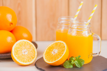 Fresh orange juice in a mason jar and orange sliced ripe on wooden table. Healthy eating concept.