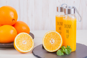 Fresh orange juice in a glass bottle and orange sliced ripe on wooden table. Healthy eating concept.