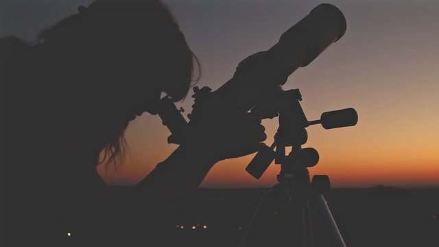 Girl looking through a telescope.