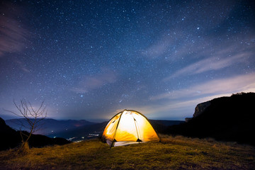 Glowing tent in the mountains under a starry sky © MIRACLE MOMENTS