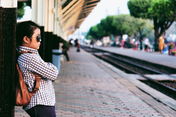 Cute girl in train station waiting to travel. Summer holiday and travel concept.