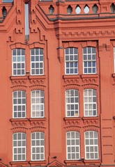 Facade of an old brick red building with windows
