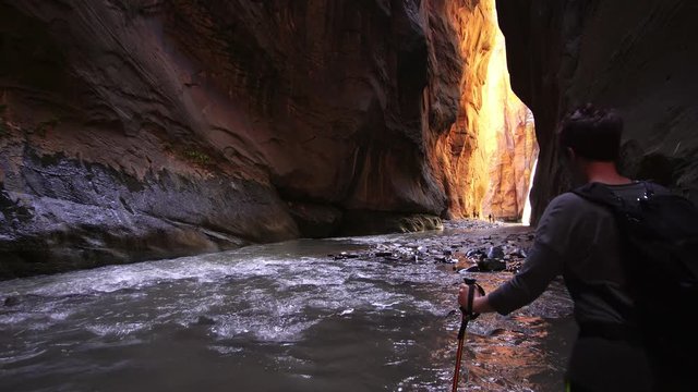Woman hiking through a slot canyon in Zion National Park.
