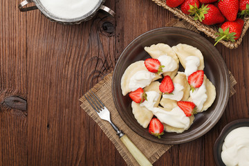 Delicious dumplings with fresh strawberries served with whipped cream and sugar.