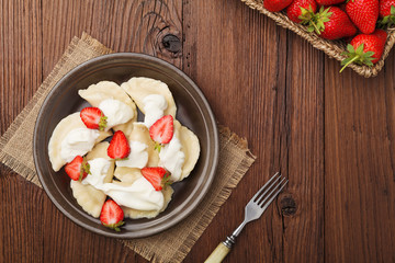 Delicious dumplings with fresh strawberries served with whipped cream and sugar.