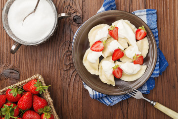 Delicious dumplings with fresh strawberries served with whipped cream and sugar.