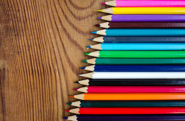 Fototapeta premium Colored pencils on a wooden board background.