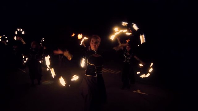 Fire show. A group of professional artists performs a variety of fire facilities. Boys and girls performed dances with fire in the night on the street in the Park
