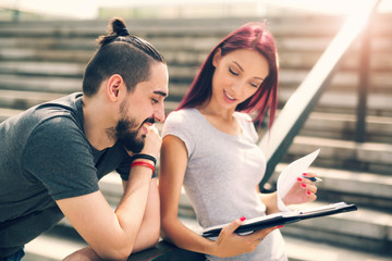 Young couple sitting in stairs at university campus