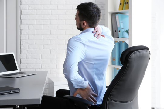 Posture Concept. Man Suffering From Back Pain While Working With Laptop At Office