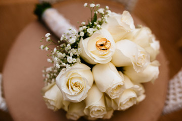 A bouquet of white roses and Golden wedding rings