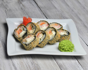 Sushi roll banzai close up. Hot roll philadelphia with shrimp on a plate on a wooden table.
