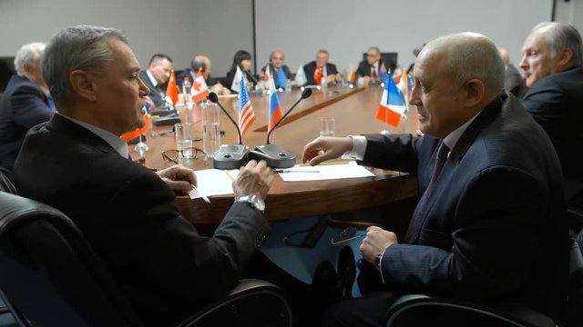 US and Russian delegates or representatives reach an agreement and shake hands at the round table of international business, political and economics debates or conference.