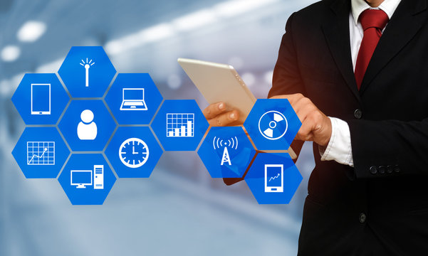 smart businessman in suit using his tablet, business and technology concept with device icon on hexagonal shaped pattern and blurred background - Powered by Adobe