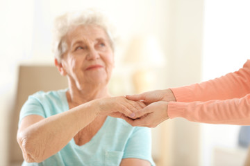 Old and young women holding hands on blurred background, closeup